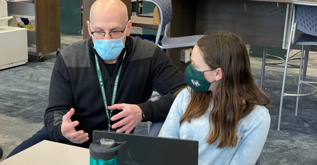 This is an image of author Gordon Korman sitting down next to a middle school student