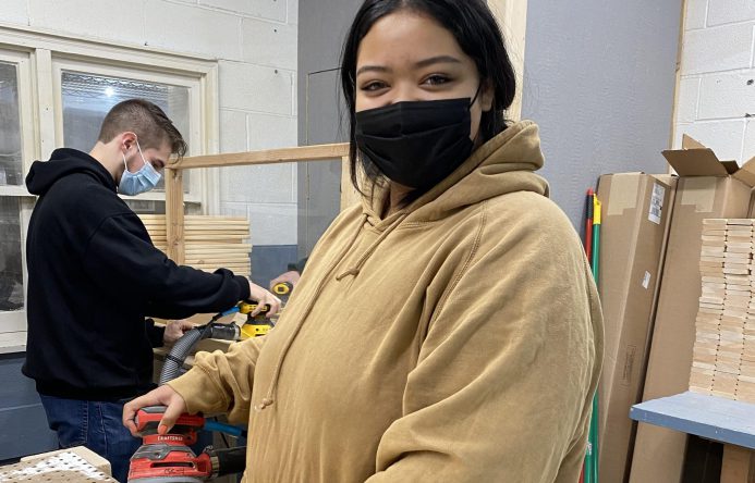 This is an image of a student holding a sanding tool