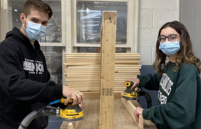 Two students working together and using sanding tools.