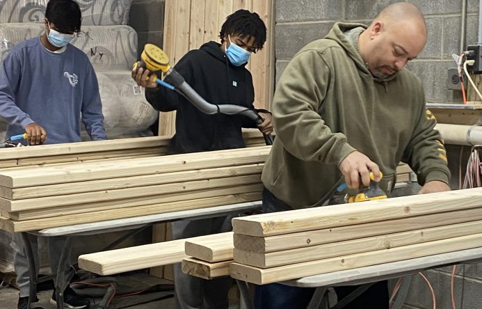 This is an image of three individuals preparing wood