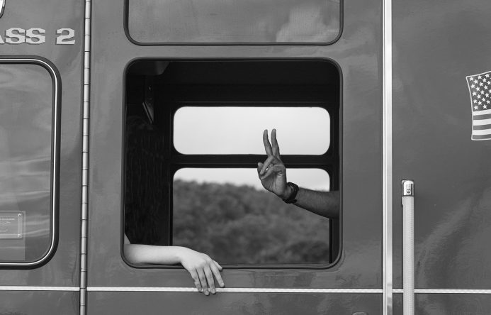 Train window with hand in the middle making a pace sign.