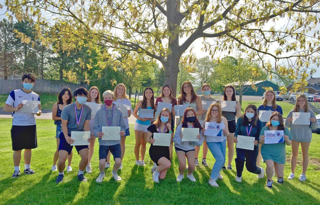 This is a group photo of more than a dozen high school students holding certificates