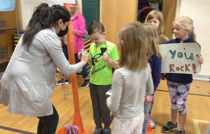 An adult puts a medal around a student's neck.