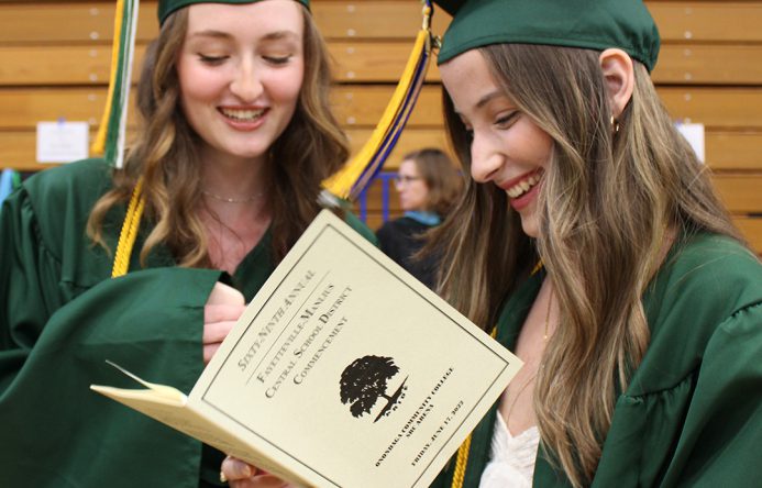 Two high school students reading the graduation program.