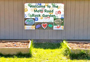 Two garden beds and a rock garden sign that says 'welcome to the Mott Road rock garden'.