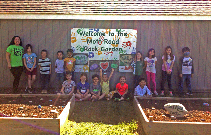 A group of students sitting and standing in the rock garden.