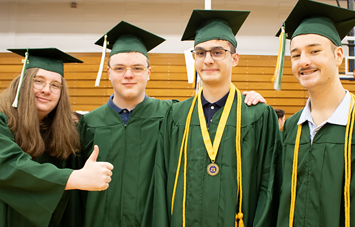 Four students standing together at graduation.