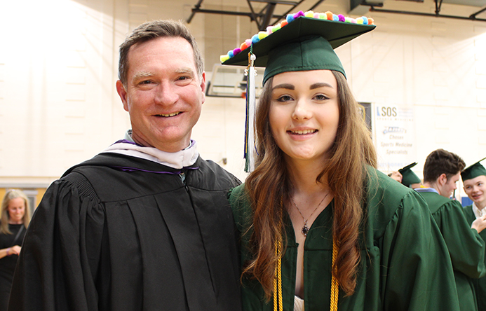 A student and teacher smiling at graduation.