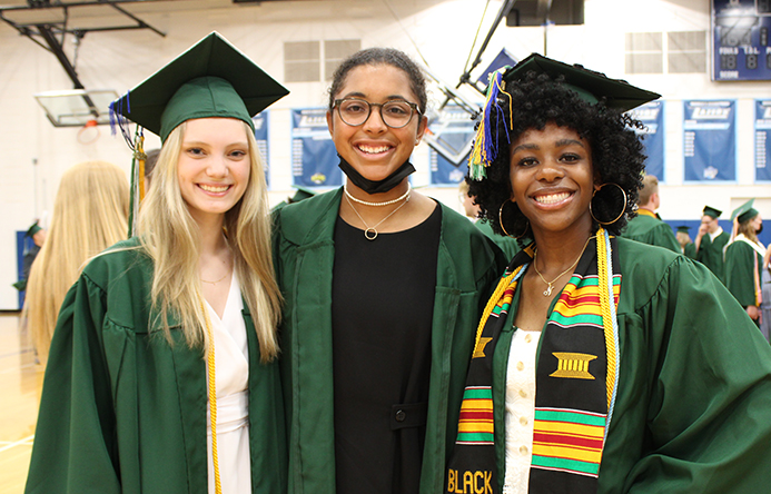 Three students inside the gymnasium at graduation.