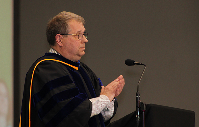 The superintendent speaking and clapping at graduation.