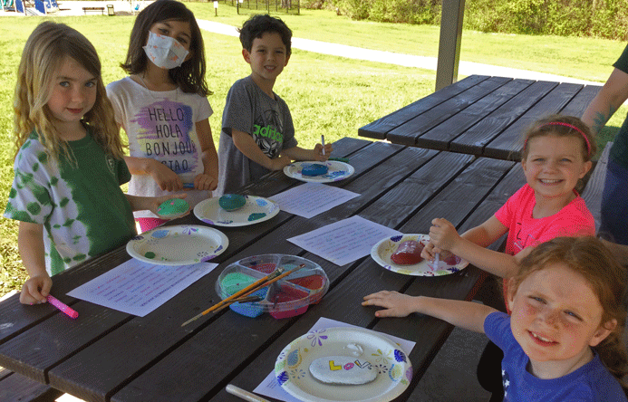 Smiling students sitting at a picnic table.