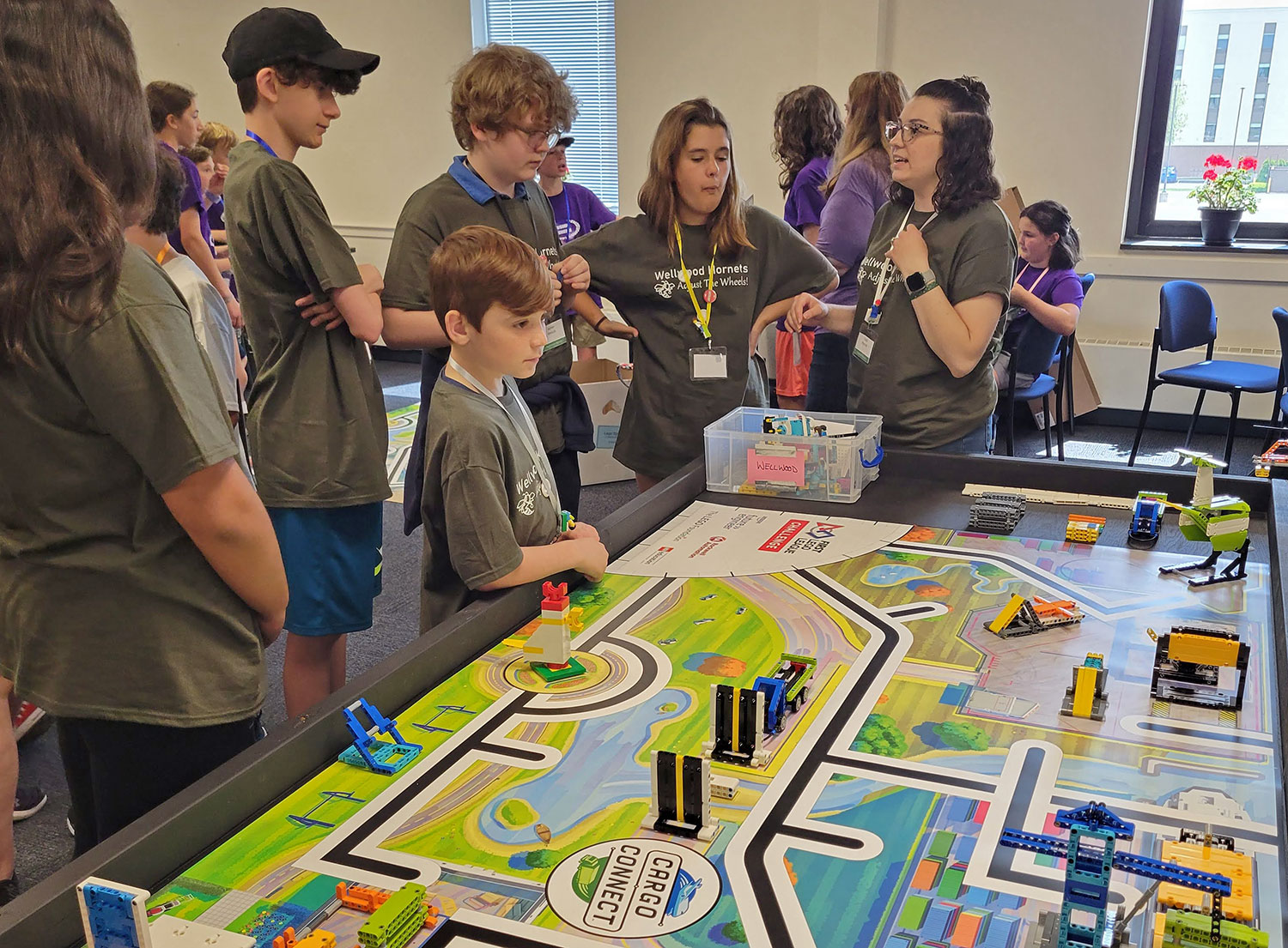 Students and an educator working together at a robotics event.