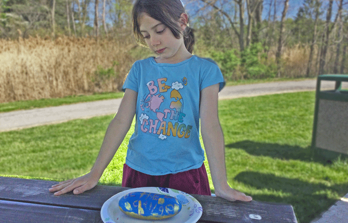 Student looking at a painted rock outside.