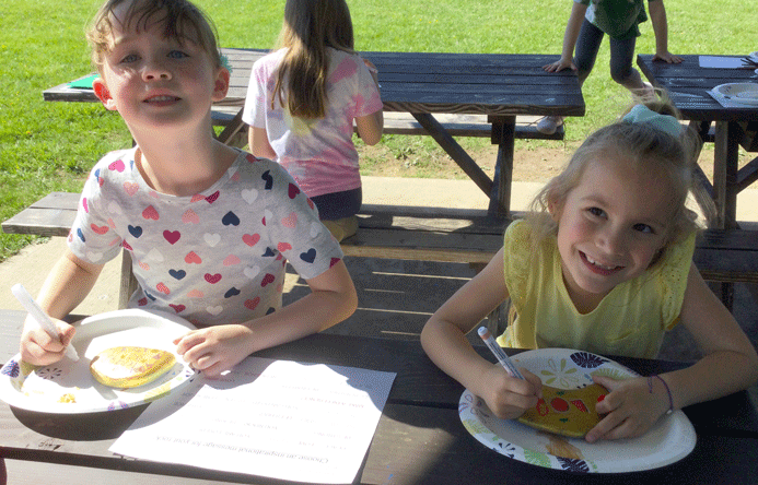 Two students painting rocks and smiling.