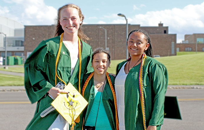 Three high school seniors standing together at graduation.