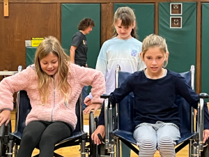 Students practice navigating wheelchairs through the gymnasium