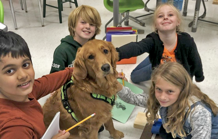 Four students encircle one of F-M's therapy dogs during class