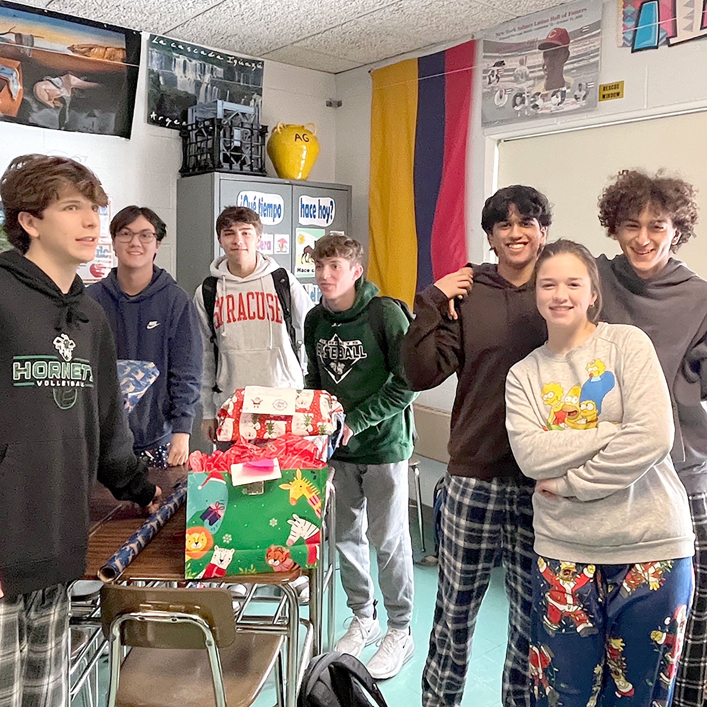 Seven high school students are in a classroom standing together for a photo