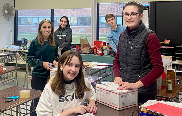 Five high school students are assembling care packages for overseas troops