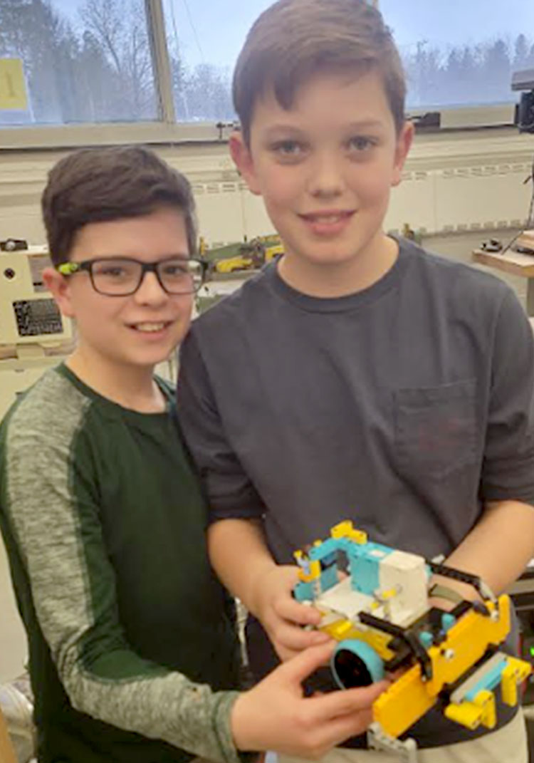 Two robotics students hold the robot that they built