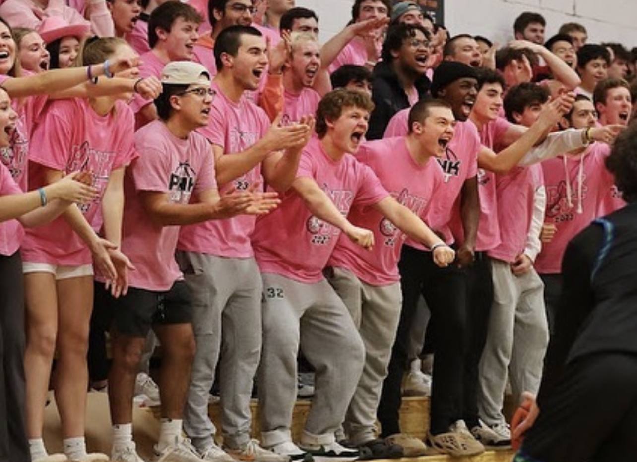 Several high school students cheer on their peers during a basketball game