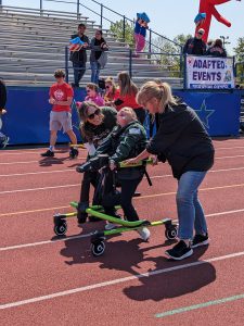 Two adult help a Special Olympian on the track