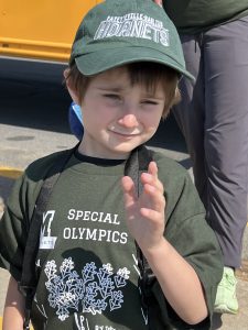 A Special Olympian, with a green baseball hat, poses for a photo