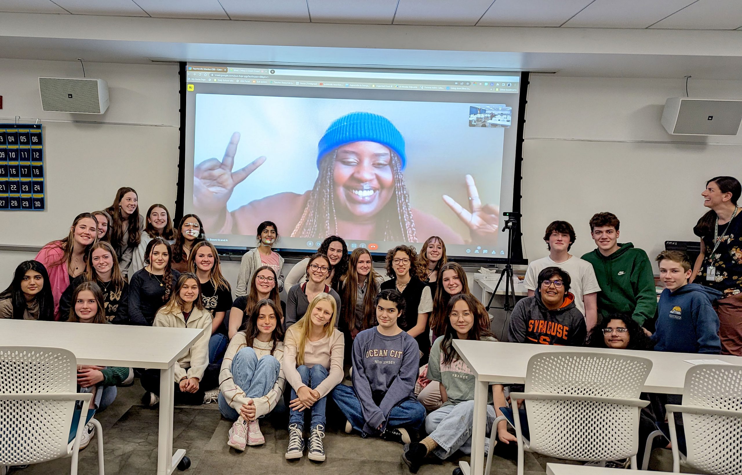 Hip hop artist Missy D is on a video screen behind a group of high school students