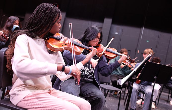 Two students play the violin during a music class at FMHS.