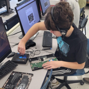 Student working on a disassembled Chromebook