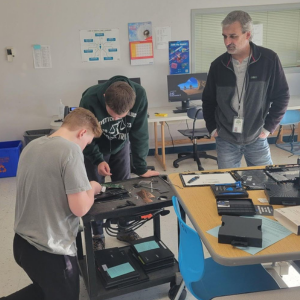 Teacher overseeing the work of two students.