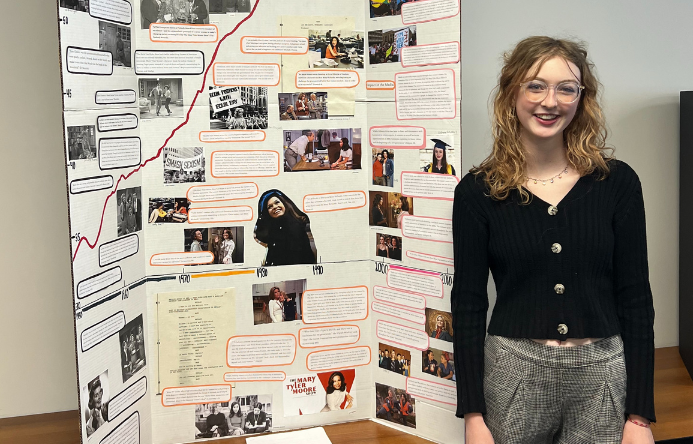 a female student standing beside a poster board project