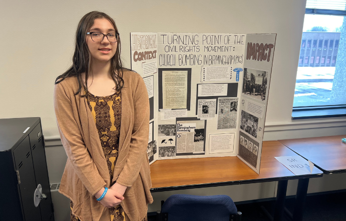 a female student standing beside a poster board project