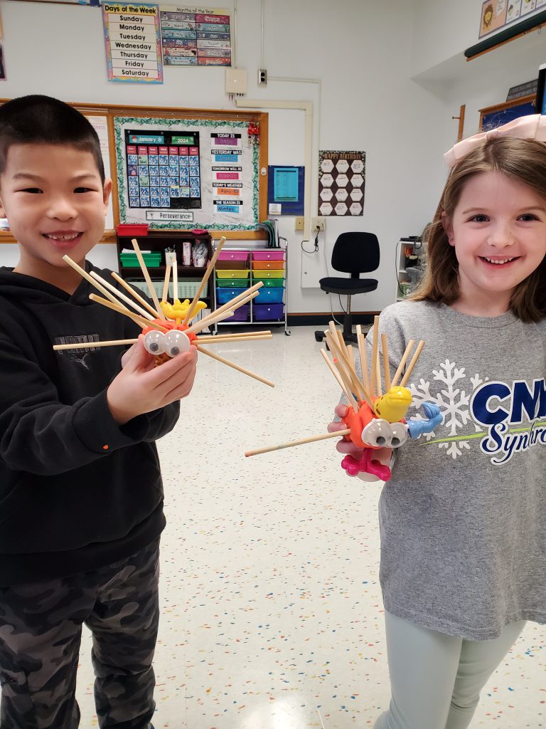 young students holding their projects smiling