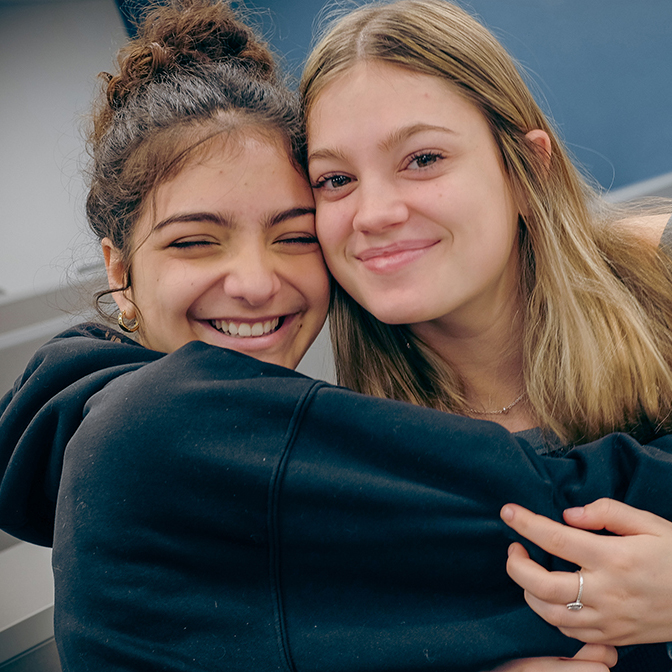 Two high school student hug tightly.
