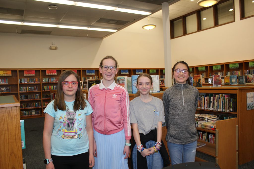 four young students in library smiling and posing together