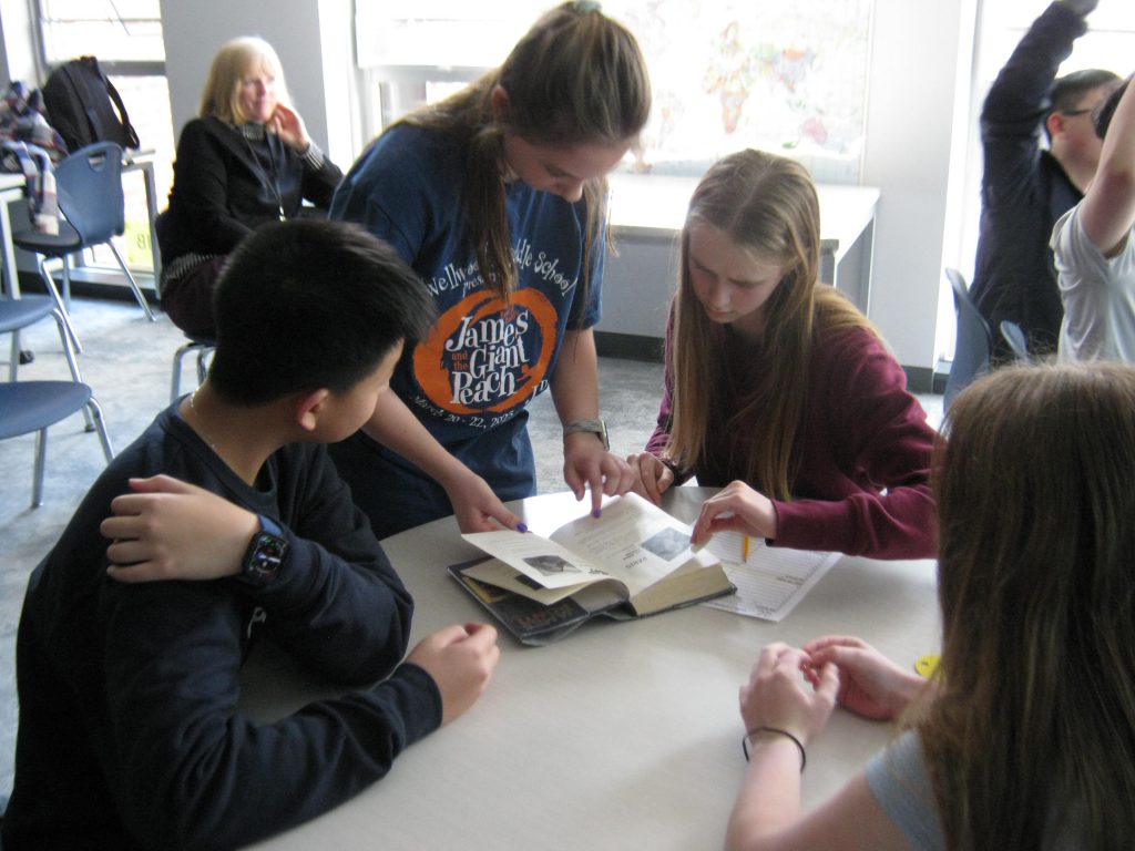 students gathered around a book looking at it during battle of books