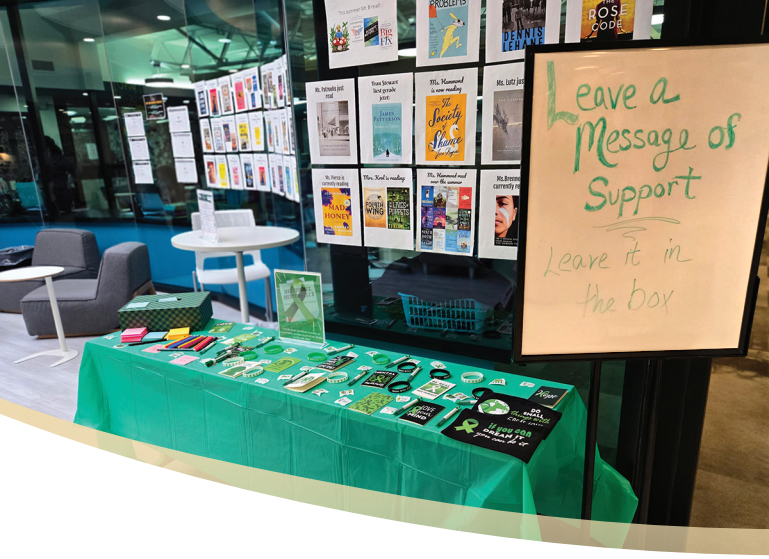 A table covered with positive knick knacks and neighboring a sign that says "Leave a message of support">