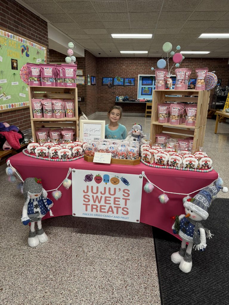 young student sitting at a stant called juju's sweet treats