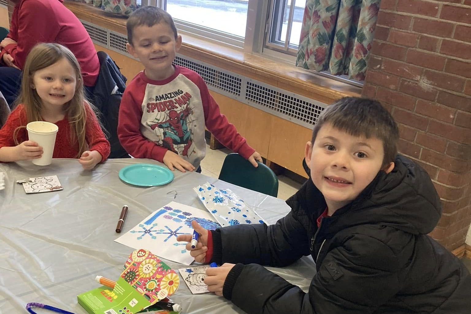 young kids sitting at table with winter colouring books