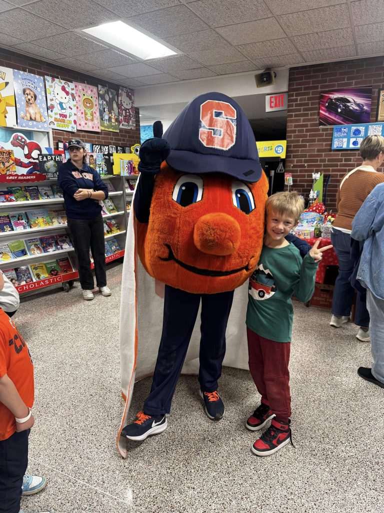young kid standing with Syracuse mascot