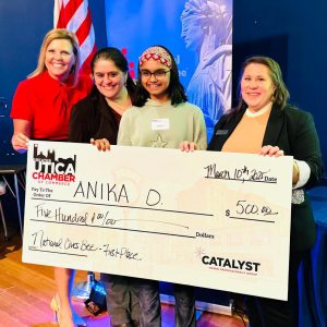 Anika Das holding a large check for $500 that signifies her win at the regional civics bee
