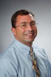 Headshot of a man in dress shirt and tie.