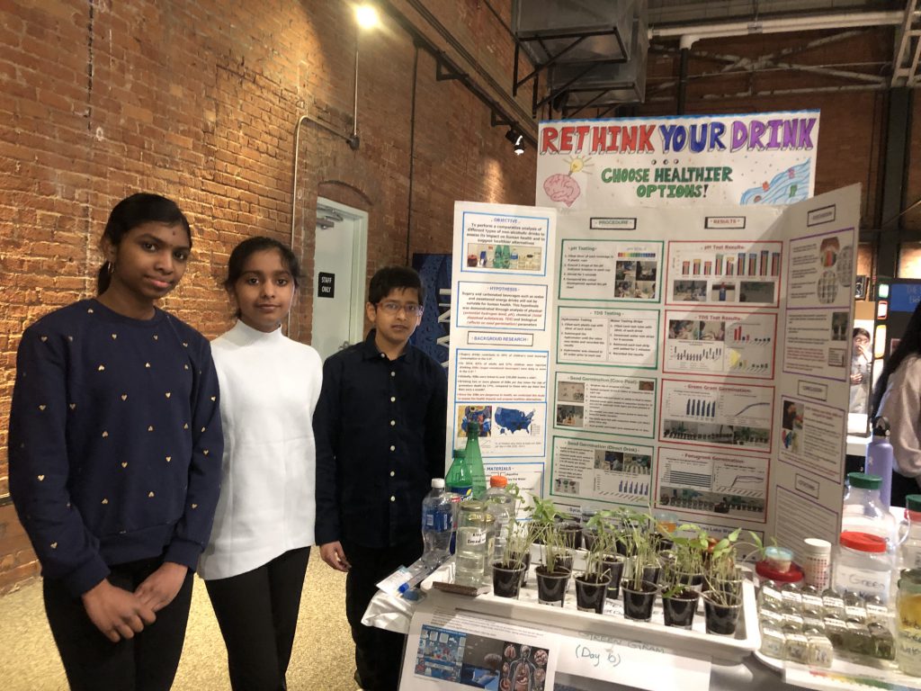 Eagle Hill Middle School students Meenakshi Thangadurai, Makizh Balaji, and Ali M. Bharmal stand in front of their poster at the CNY Science and Engineering Fair Competition.