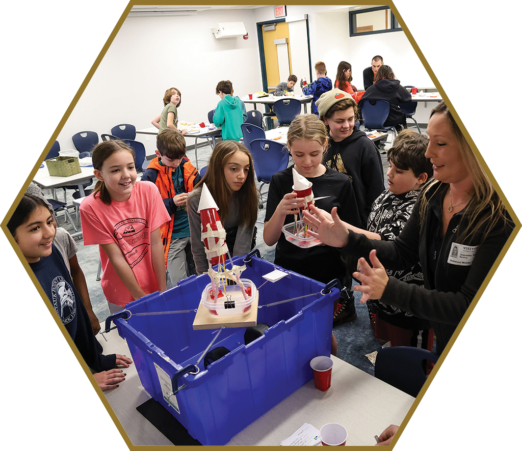 A teacher works with middle school students as they experiment with STEM sculptures.