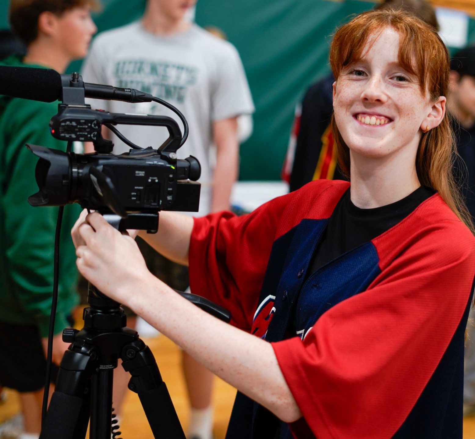 A high school AV student proudly smiles from behind the camera.