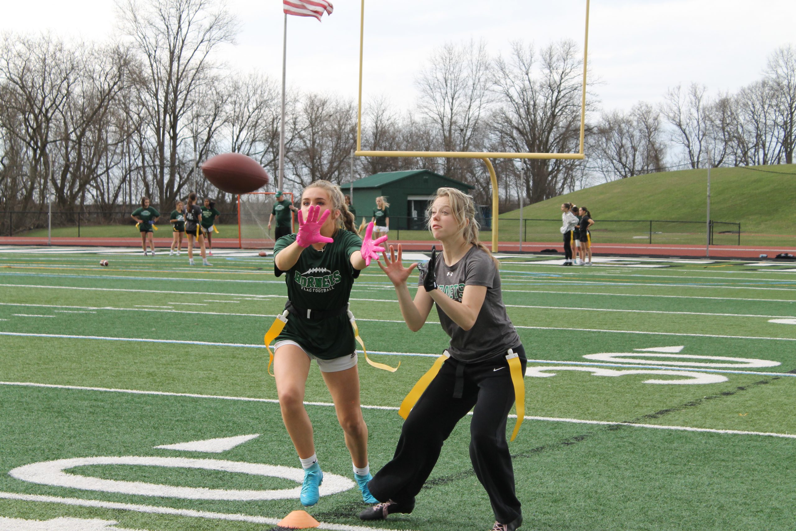 Two Girls Flag Football team members attempt to catch a football.