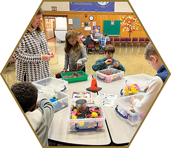 A teacher looks over elementary students working at a sensory table.