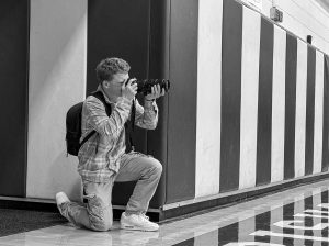 An FMHS student takes a photo on the sidelines of a basketball game.