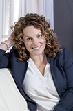 Headshot of a woman leaning against a chair.